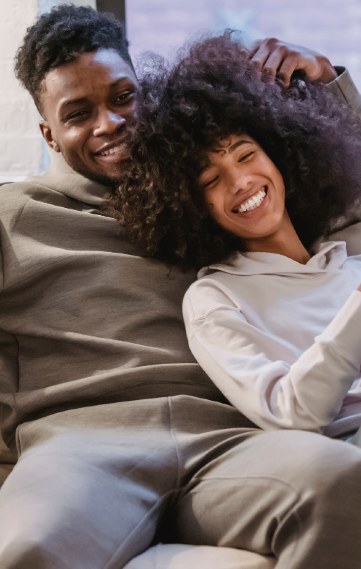 Smiling couple in casual clothes relaxing together on a cozy couch at home.